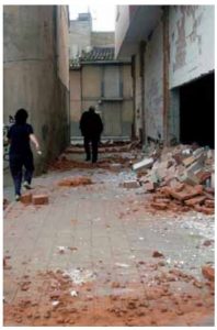 Persones caminant per un carrer en ruïnes.